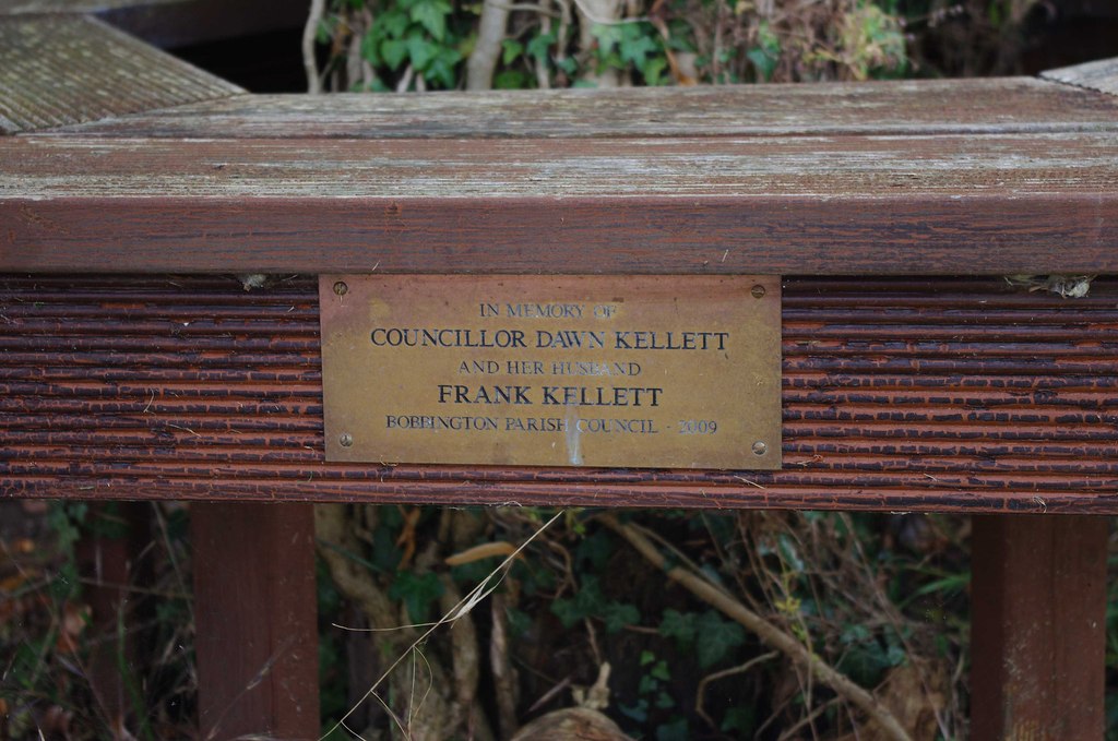 Memorial plaque on bench seat in car park of Holy Cross Church, Bobbington